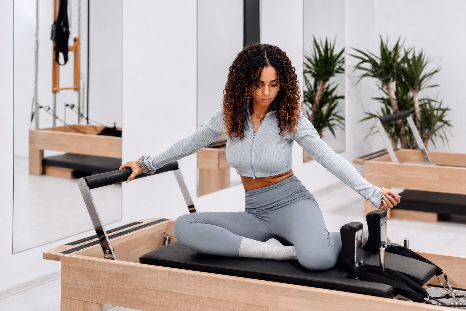 Woman practicing Pilates on a reformer in a bright neutral studio