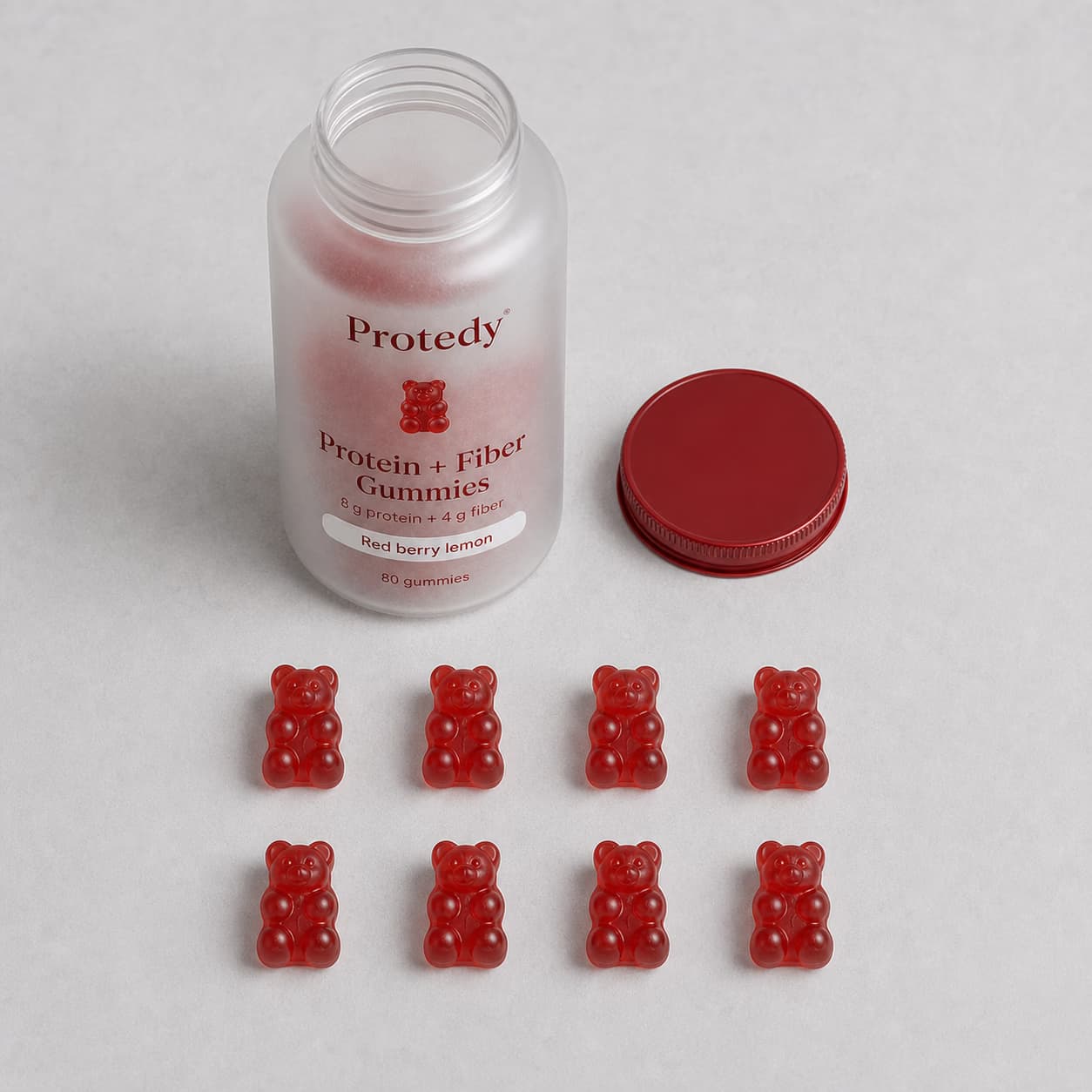 An open PROTEDY bottle beside eight ruby gummies